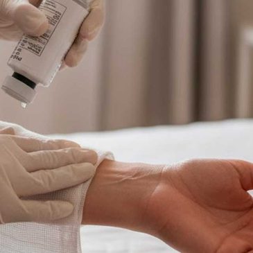 Curativo em casa: Mãos de enfermeira realizando curativo em casa com gaze estéril e soro fisiológico, ao lado do paciente, em ambiente domiciliar iluminado